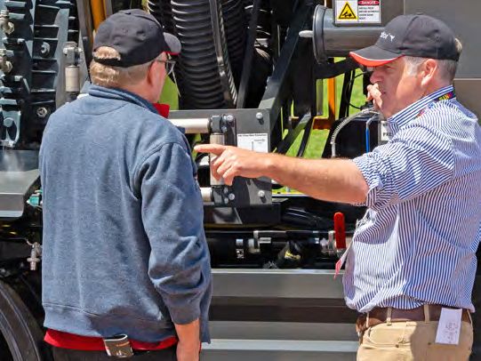 Two visitors inspecting equipment on a vacuum truck