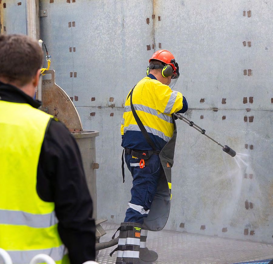 Operator water jetting a steel wall